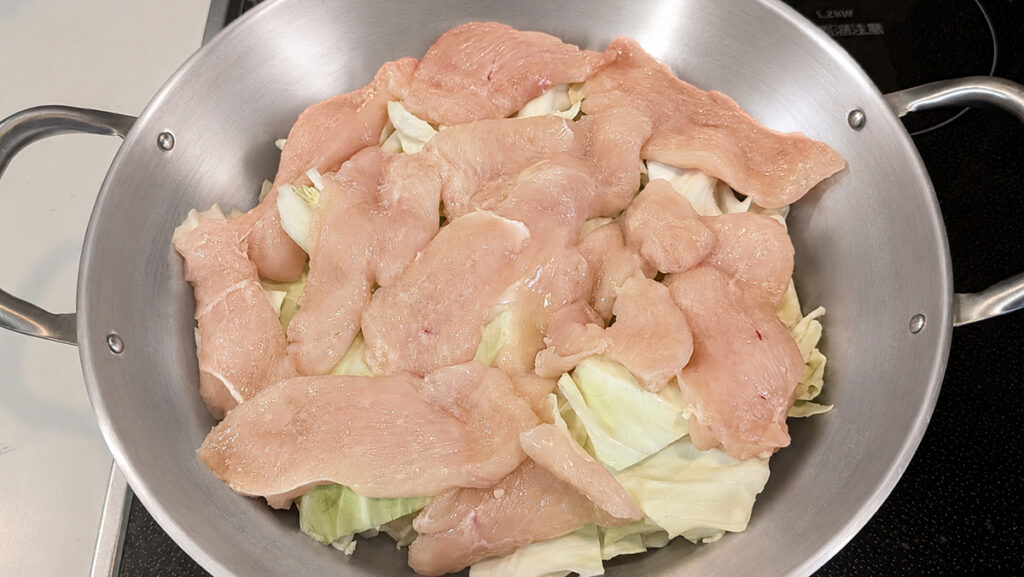 キャベツを敷き詰め、その上にそぎ切りにした鶏むね肉を重ならないように載せます。