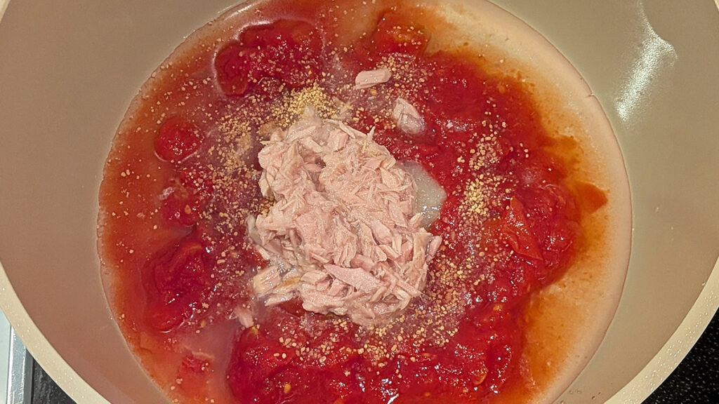 鍋にトマト缶とツナ缶を入れて煮る様子